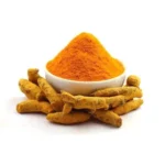 Organic Amba Haldi powder in a white bowl surrounded by raw wild turmeric roots for natural skin care.