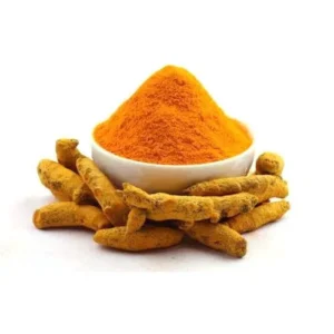 Organic Amba Haldi powder in a white bowl surrounded by raw wild turmeric roots for natural skin care.